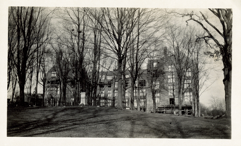 A side view of Clapp Building, with leafless trees and Mary Lyon's grave sitting in front of it. There is scaffolding on the bottom right of Clapp Building.