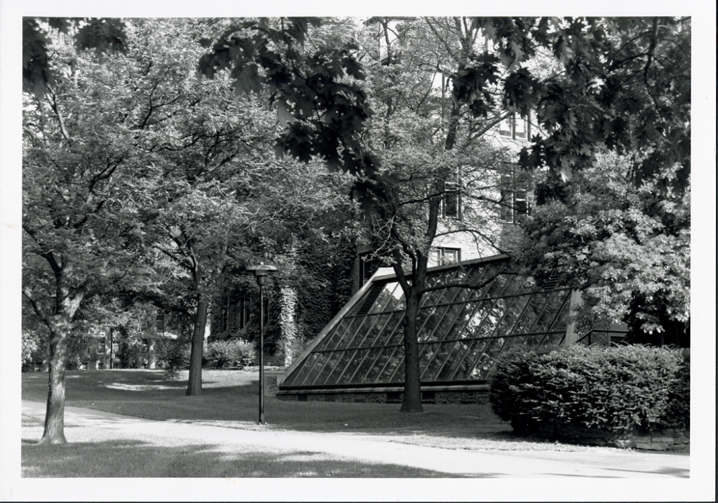 The Clapp Greenhouse from outside. It is surrounded by trees and shrubs.