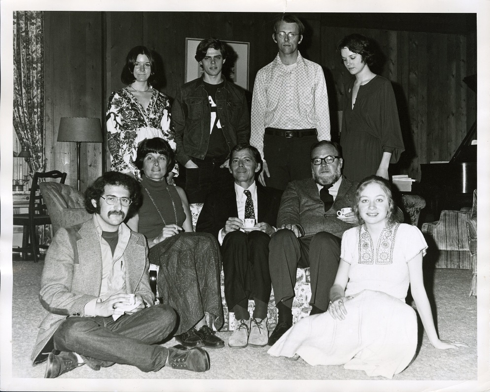 Contestants and judges pose in a sitting room, three on a couch, two on the floor, and four standing behind the couch.