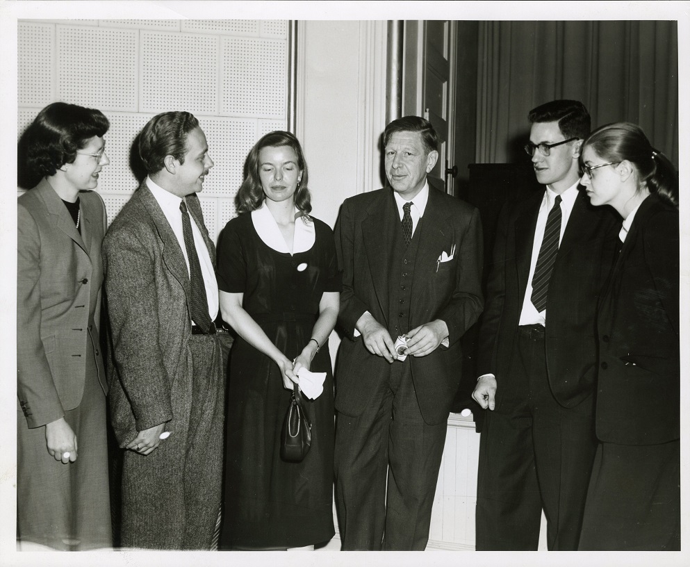 Poet W.H. Auden stands surrounded by the five Glascock contestants. All are dressed in suits and dresses.