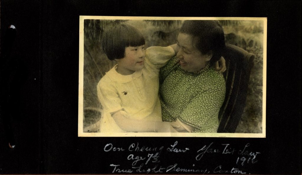 Yau Tsit Law, class of 1916, wears a green Chinese cheongsam and smiles at her daughter, Oon Cheung Law, who sits on her lap.