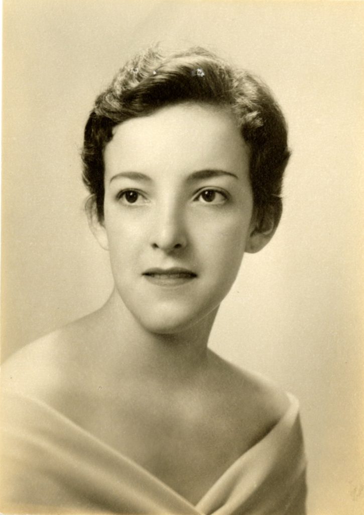 Isabel Magali Luque-Calero, shown in a waist-up shot, wears a light-colored strapless top with her hair tied up. Llamarada 1957.