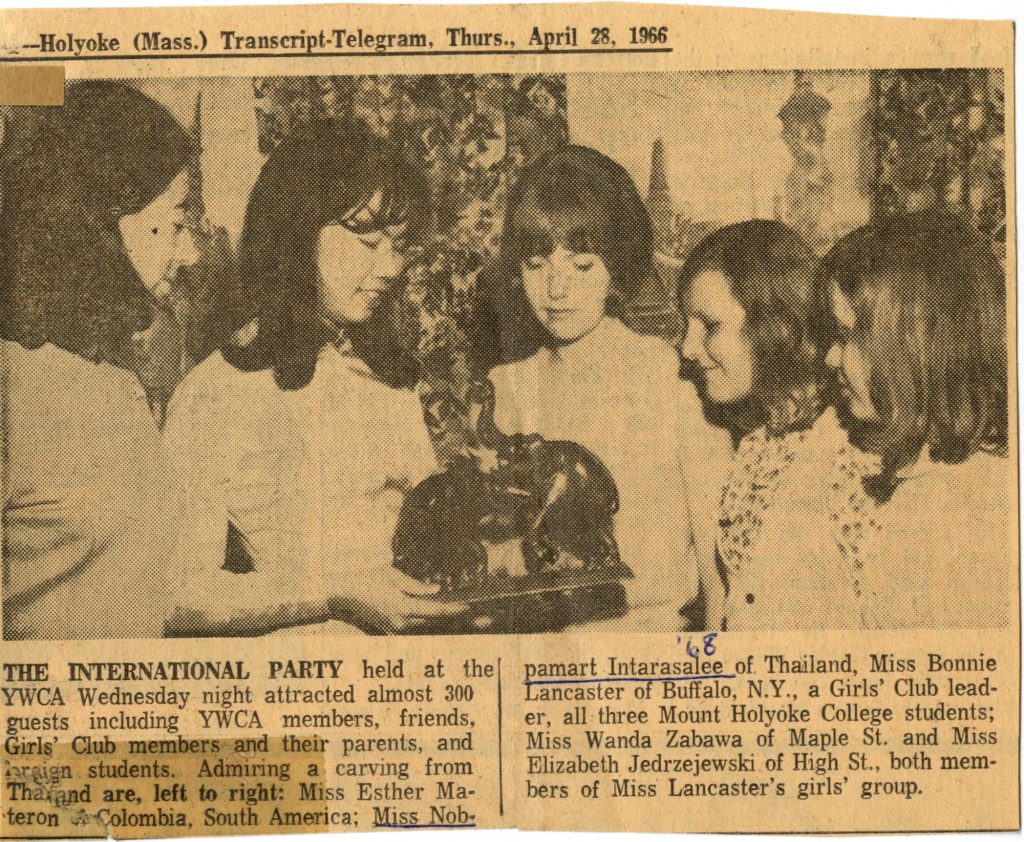Faded yellow newspaper clippings, Nopamart Intarasalee, class of 1968, was featured in the Holyoke Transcript-Telegram on April 28, 1966. There are five girls in the photo; Nopamart Intarasalee is the second from the left holding a statue of two elephants.