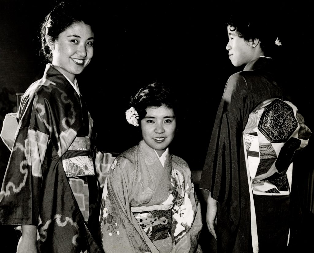 Three students in flower-patterned and geometrically-patterned Japanese kimonos.