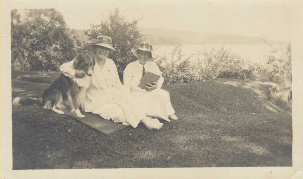 Mount Holyoke President Mary Emma Woolley and Professor Jeannette Marks with a dog on a hillside, circa 1930s