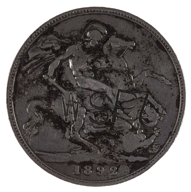 The reverse shows a man holding a sword on a horse with the letters WSPU stamped over him. It also says that the coin is from 1892