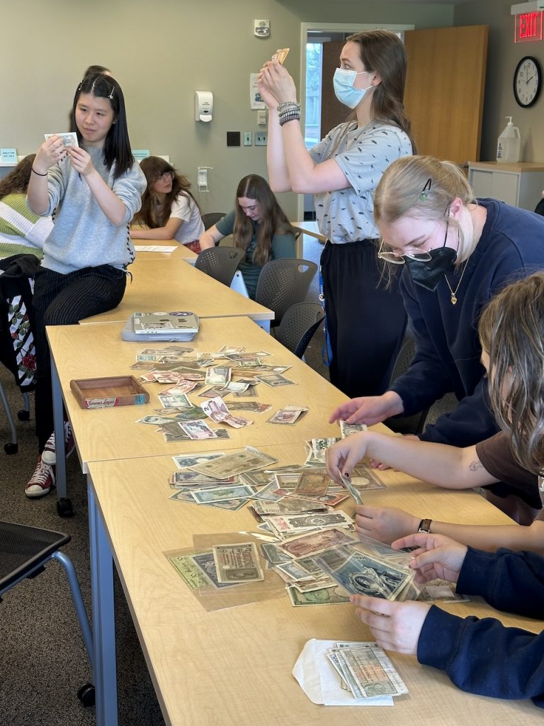 Image of students examining different banknotes and coins in class.