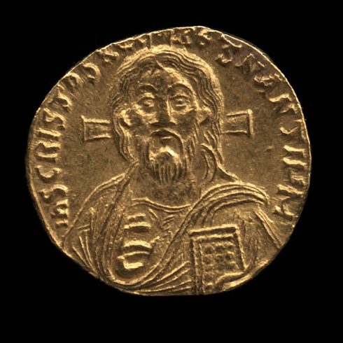 A gold coin set against a black background. The coin is slightly misshapen and depicts Jesus surrounded by text.