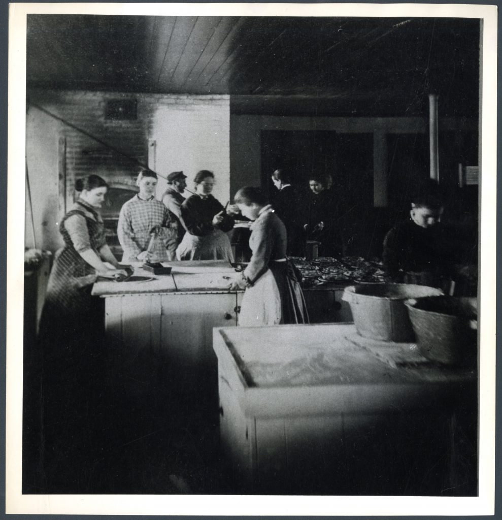 Students stand around tall tables rolling dough and preparing pies.