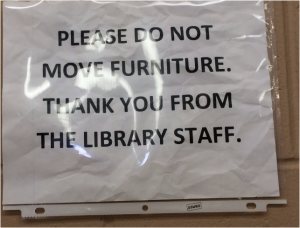 Image of a printed, wrinkled sign shoved in a plastic sleeve telling patrons not to do something.